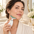 Woman holding the white curved-head massager against the side of her jawline.